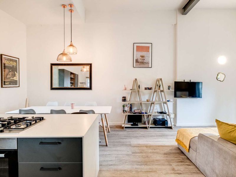 Modern open-plan living area featuring a sleek kitchen island with integrated gas hob, pendant lighting, and durable laminate flooring throughout the space.