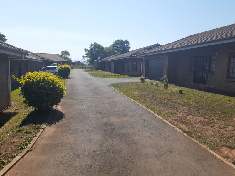 A view of the townhouse complex driveway and exterior facades featuring brick construction and tiled roofing.
