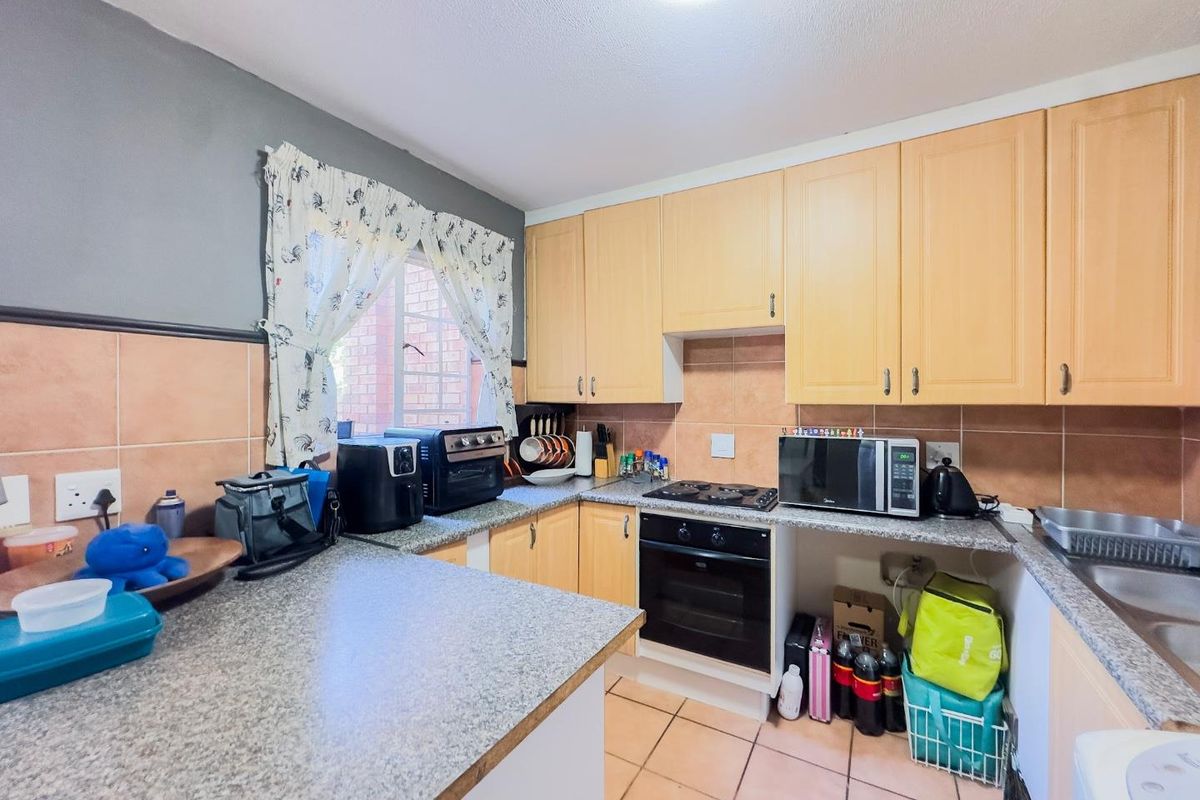 A functional kitchen featuring light wood cabinetry, granite countertops, a built-in oven, gas hob, and tiled backsplash, offering a practical layout for daily cooking.