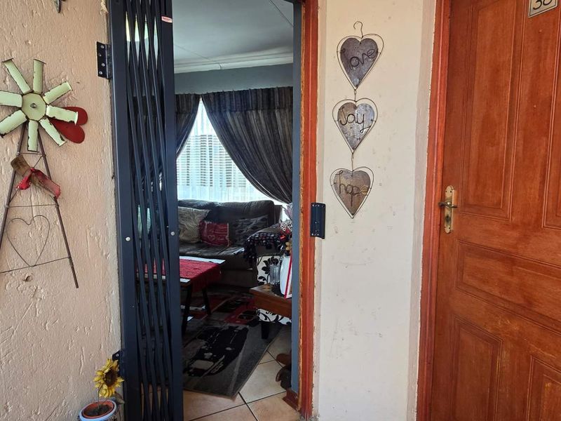 Entrance area featuring a solid timber front door and a retractable security gate leading into the main living space.