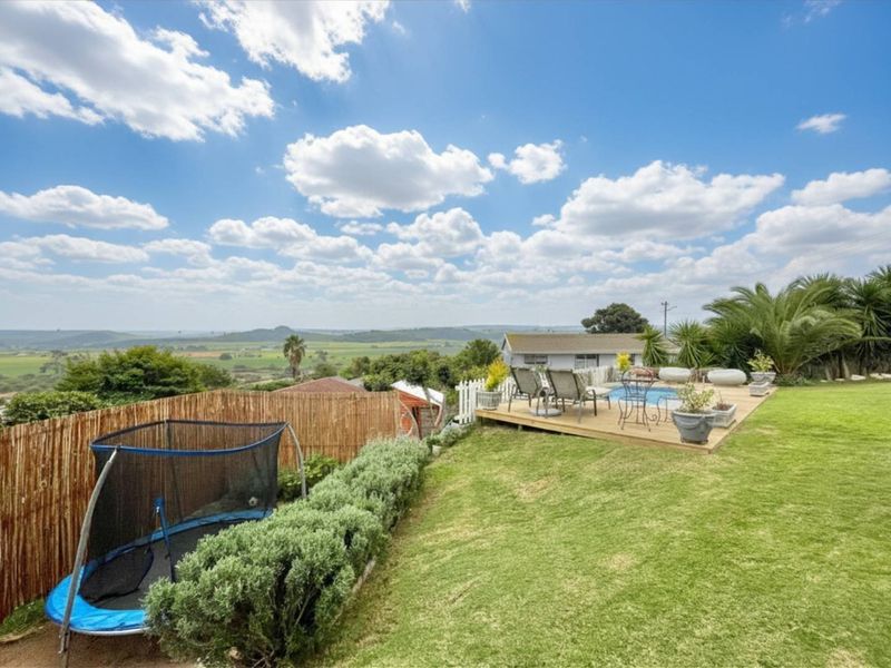 Outdoor entertainment area featuring a swimming pool, timber decking, and expansive views over the surrounding landscape.