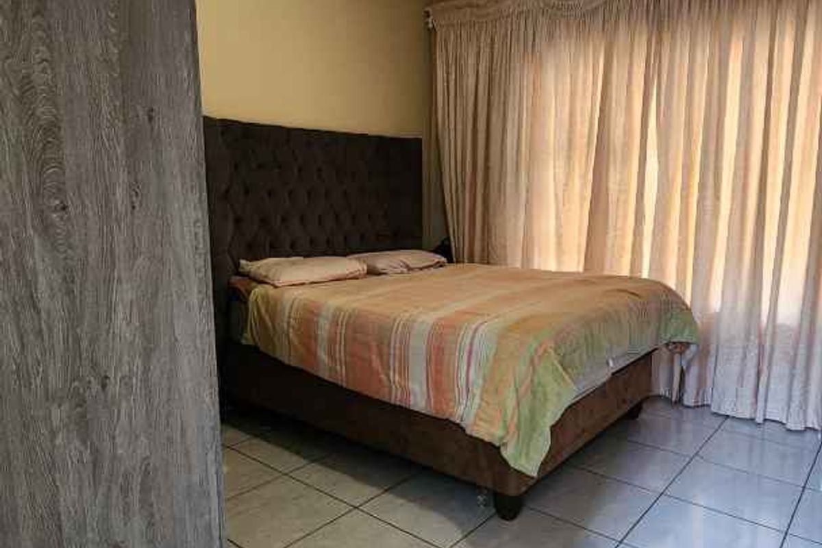 A bedroom featuring tiled flooring, crown molding, and a built-in wardrobe, providing a functional and neutral living space.