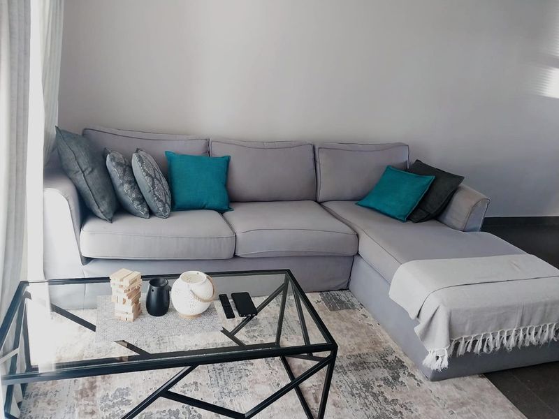 A comfortable living room area featuring neutral tiled flooring and natural light from the adjacent window.