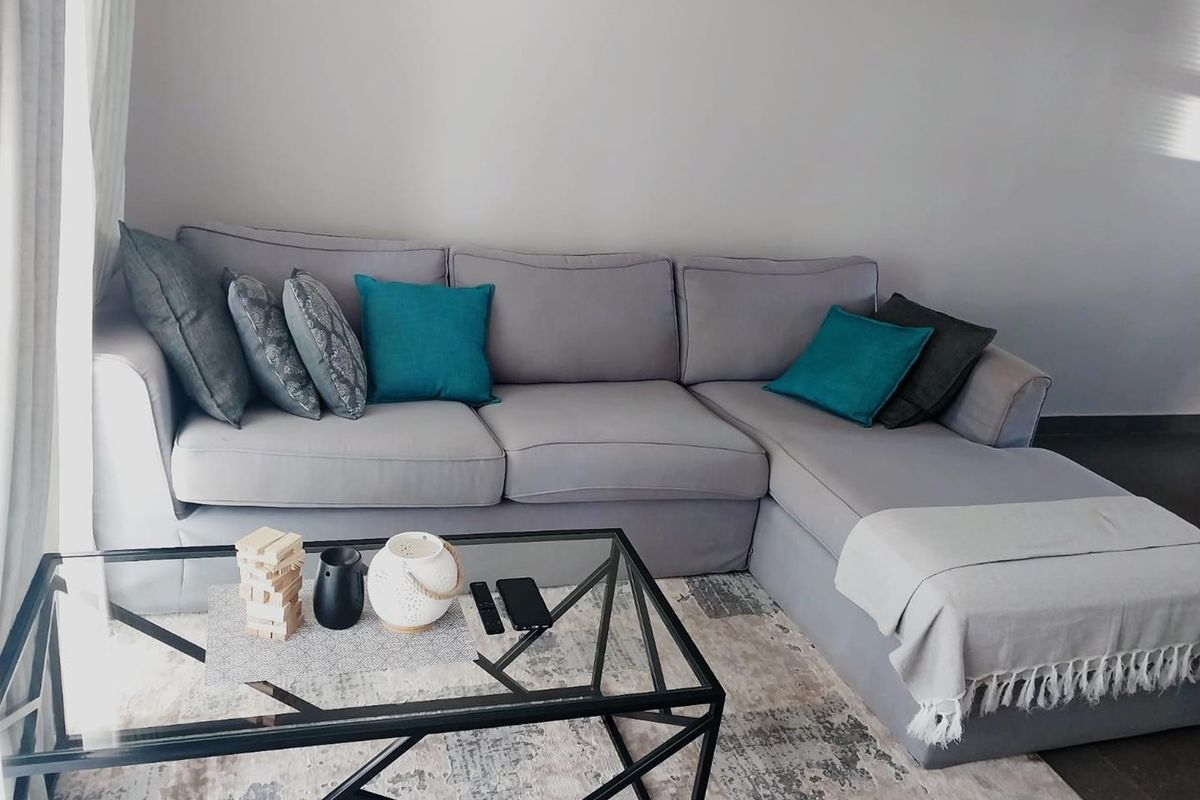 A comfortable living room area featuring neutral tiled flooring and natural light from the adjacent window.