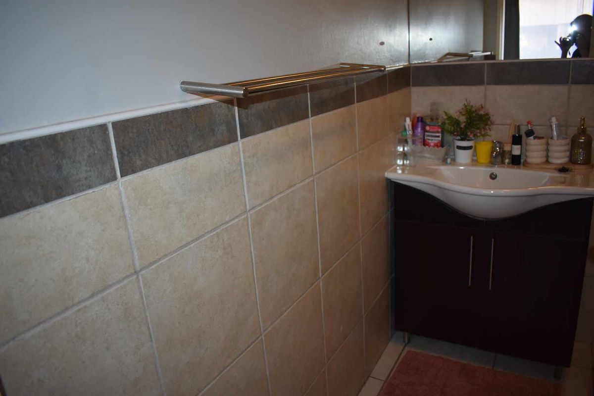 A bathroom featuring a vanity cabinet with an integrated basin, wall-mounted towel rail, and tiled wall finishes.