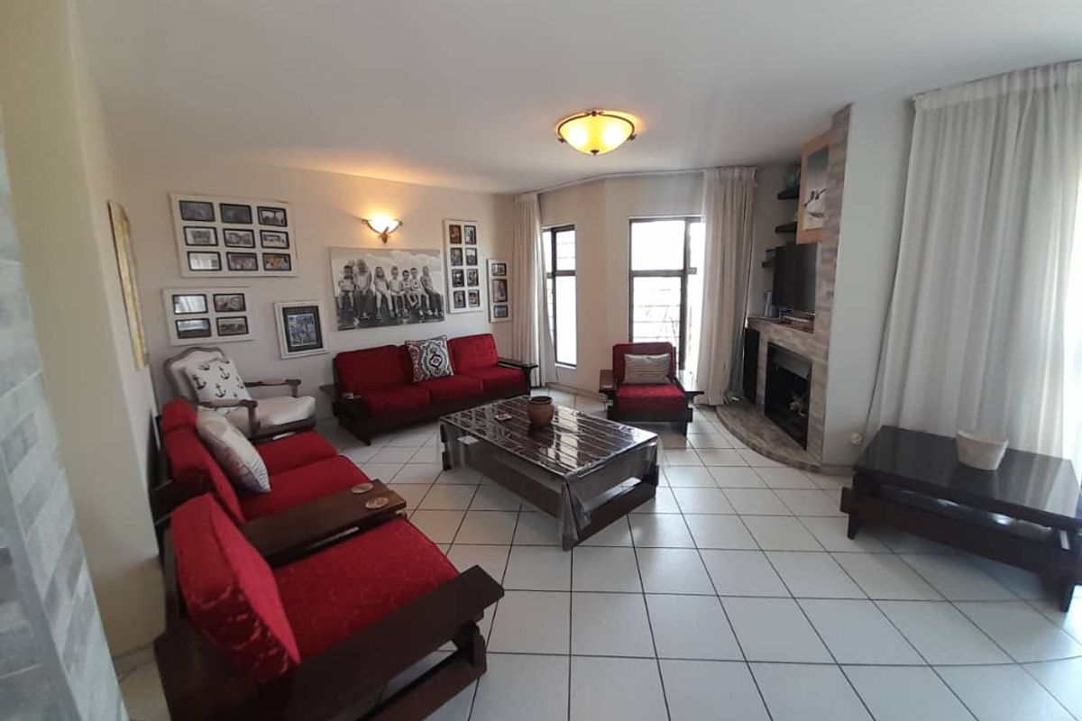 Spacious living room featuring tiled flooring, a built-in fireplace with stone cladding, and large windows allowing for natural light.
