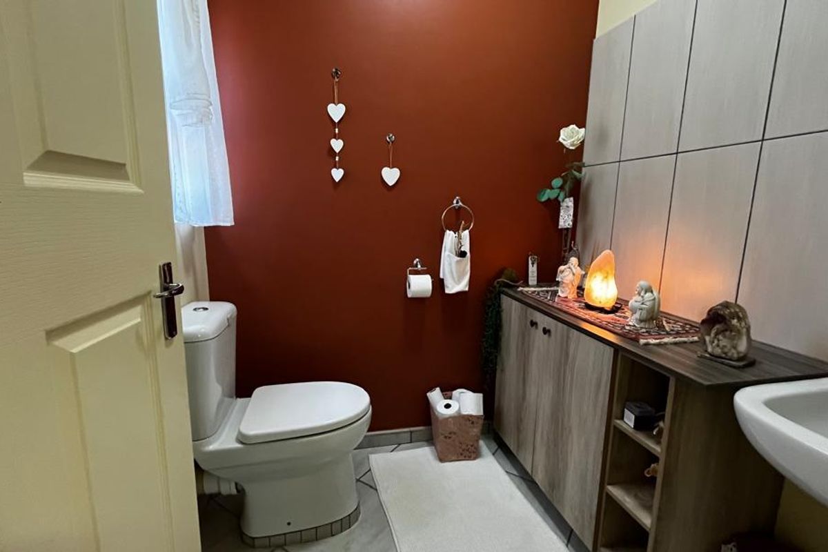 A functional bathroom featuring a toilet, wall-mounted basin, and built-in vanity cabinetry with tiled splashbacks.