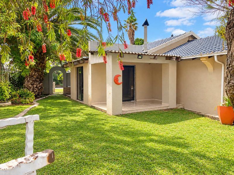A view of the rear exterior featuring a covered patio, tiled roof, and a well-maintained garden area.