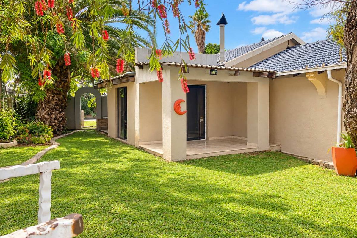 A view of the rear exterior featuring a covered patio, tiled roof, and a well-maintained garden area.
