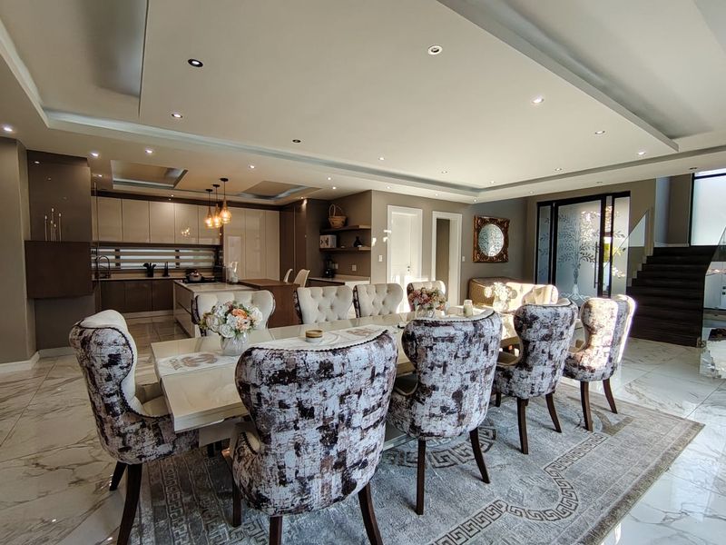 Spacious open-plan dining and kitchen area featuring modern cabinetry, a central island, recessed ceiling lighting, and elegant marble-look flooring.