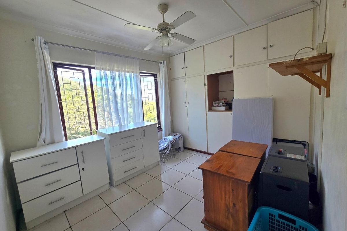 Bedroom featuring built-in cupboards, tiled flooring, and a ceiling fan, with security bars on the windows.