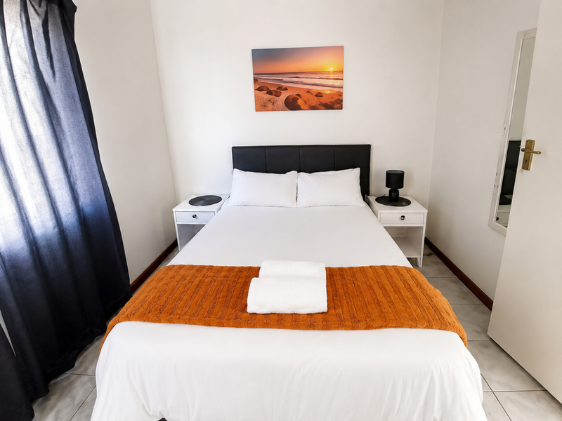A well-maintained bedroom featuring neutral tiled flooring and clean white walls, providing a bright and comfortable living space.