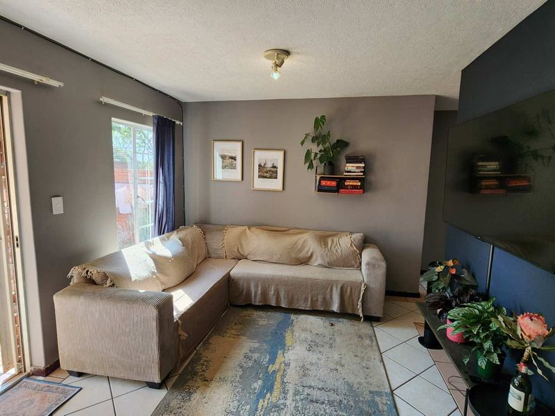A comfortable living room featuring tiled flooring and a sliding glass door that provides direct access to the outdoor garden area.