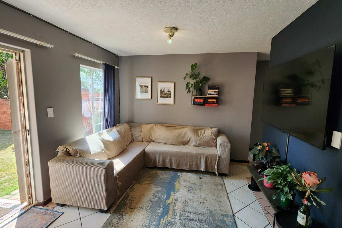 A comfortable living room featuring tiled flooring and a sliding glass door that provides direct access to the outdoor garden area.