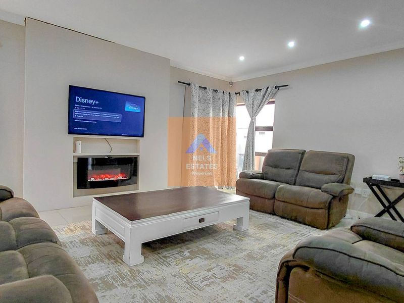 A well-maintained living room featuring a built-in electric fireplace, recessed downlighting, and neutral tiled flooring.