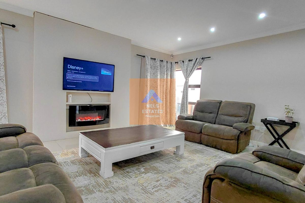 A well-maintained living room featuring a built-in electric fireplace, recessed downlighting, and neutral tiled flooring.