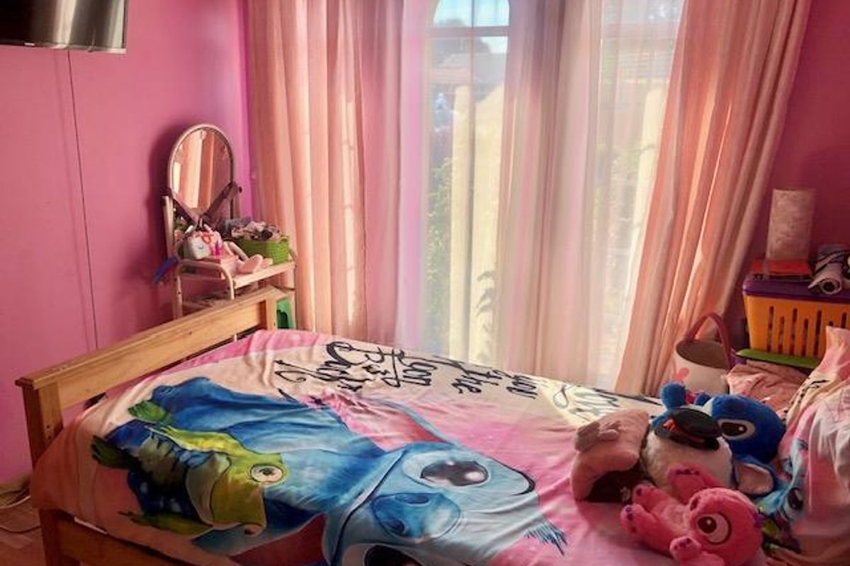 A bedroom featuring an arched window with curtains, providing natural light and a view of the exterior.