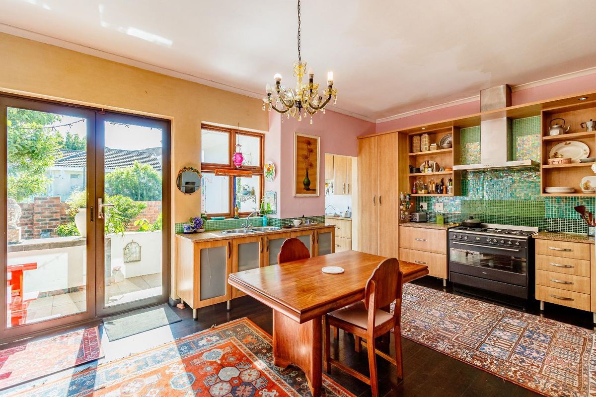 Spacious kitchen featuring wooden cabinetry, mosaic tile backsplash, integrated oven with extractor fan, and direct access to the outdoor patio area.