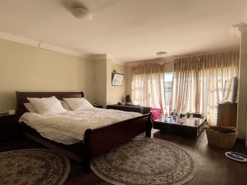 Spacious bedroom featuring laminate flooring, built-in cupboards, and sliding glass doors leading to an outdoor area, with crown molding detailing.