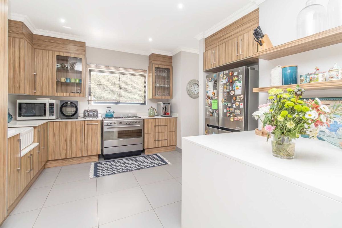 Modern kitchen featuring wood-grain cabinetry, stone countertops, a stainless steel gas stove, and a large central island with ample workspace.