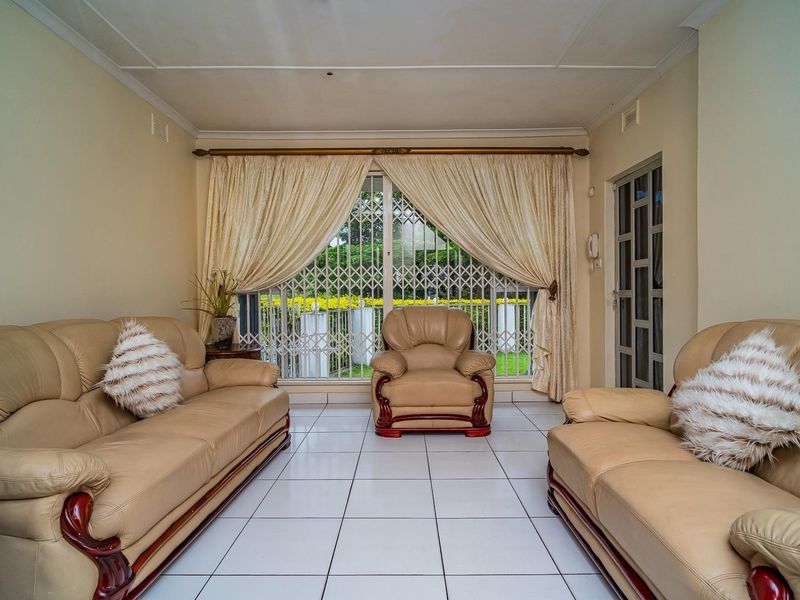 A living room featuring white tiled flooring, a large sliding glass door with a security gate, and neutral wall finishes.