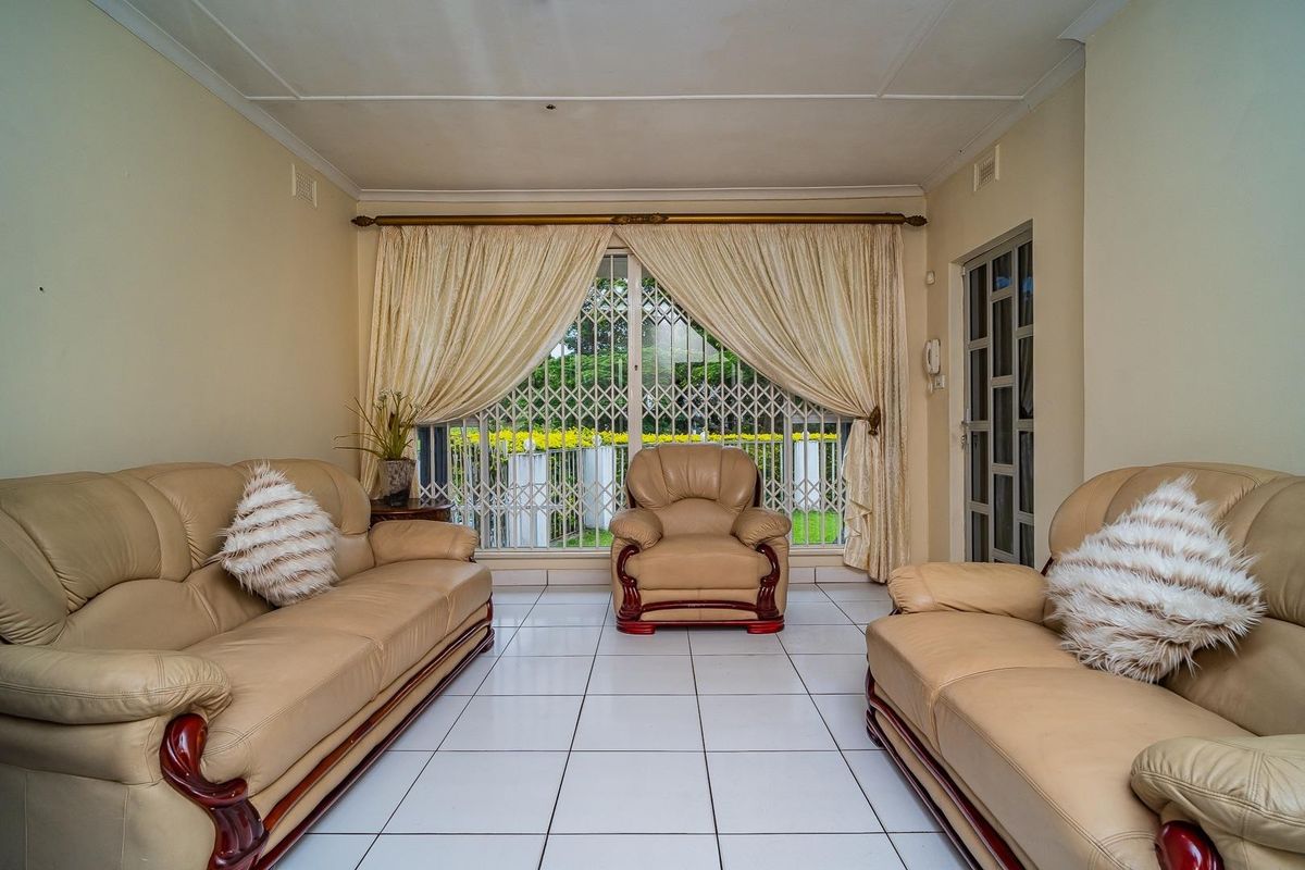 A living room featuring white tiled flooring, a large sliding glass door with a security gate, and neutral wall finishes.
