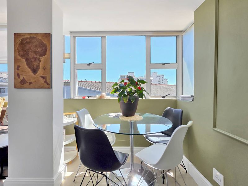 A bright dining area featuring large windows that provide natural light and an urban view, accented with decorative wall moulding.