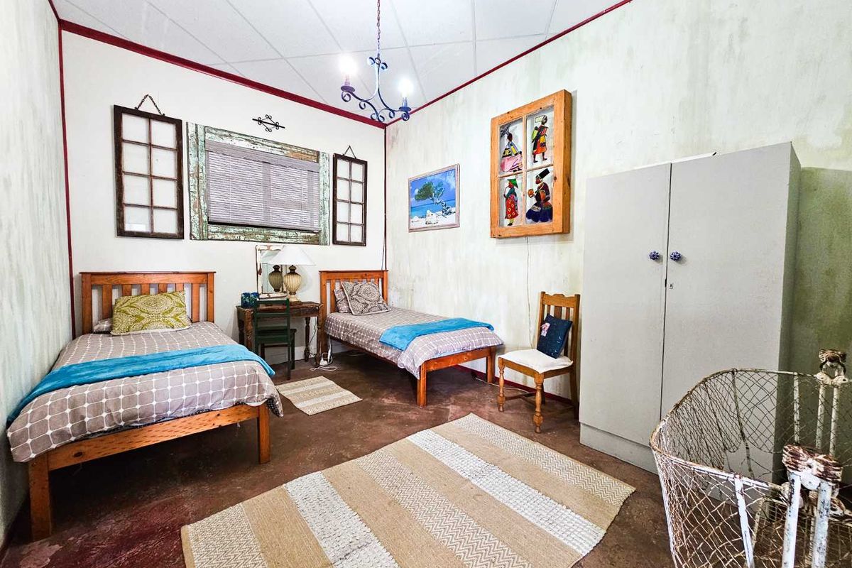 A bedroom featuring concrete flooring, a central chandelier, and built-in storage, offering a functional space with potential for cosmetic updates.