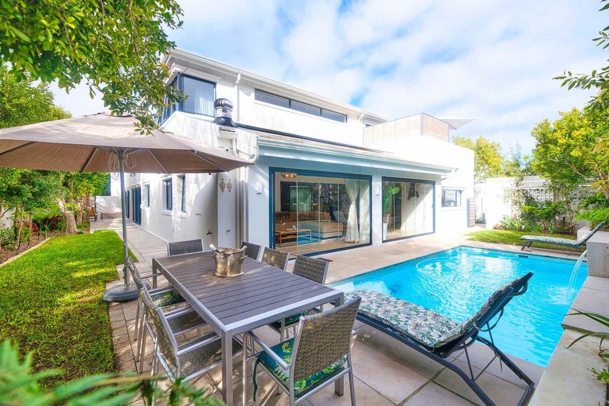 A well-maintained rear exterior featuring a swimming pool, paved patio area, and seamless indoor-outdoor flow through large sliding glass doors.