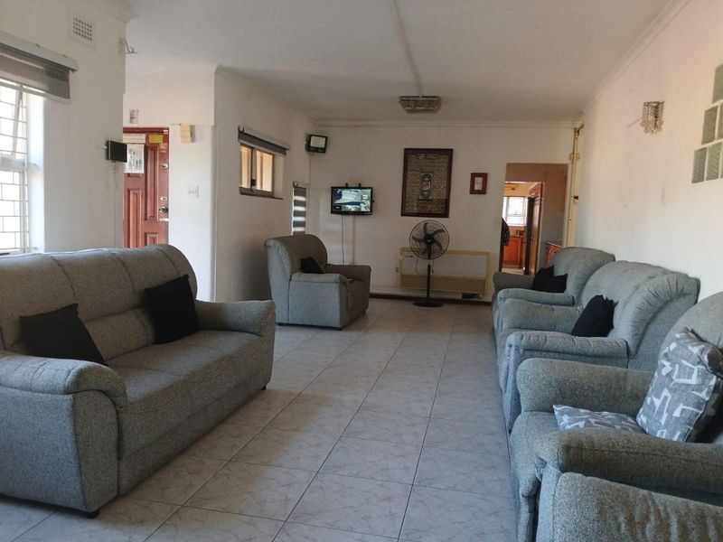Spacious living room featuring ceramic tiled flooring, coved ceilings, and a glass block feature, offering a functional layout with direct access to the kitchen area.