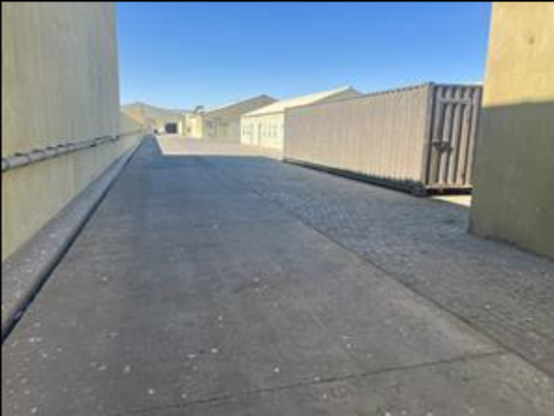 Exterior view of an industrial property showing a concrete driveway between building structures.