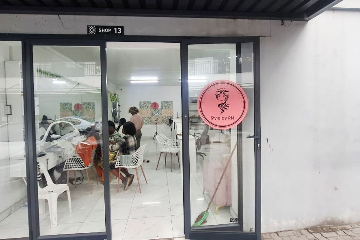 Entrance view of a commercial shop unit featuring aluminium framed glass doors and tiled flooring, currently operating as a salon.
