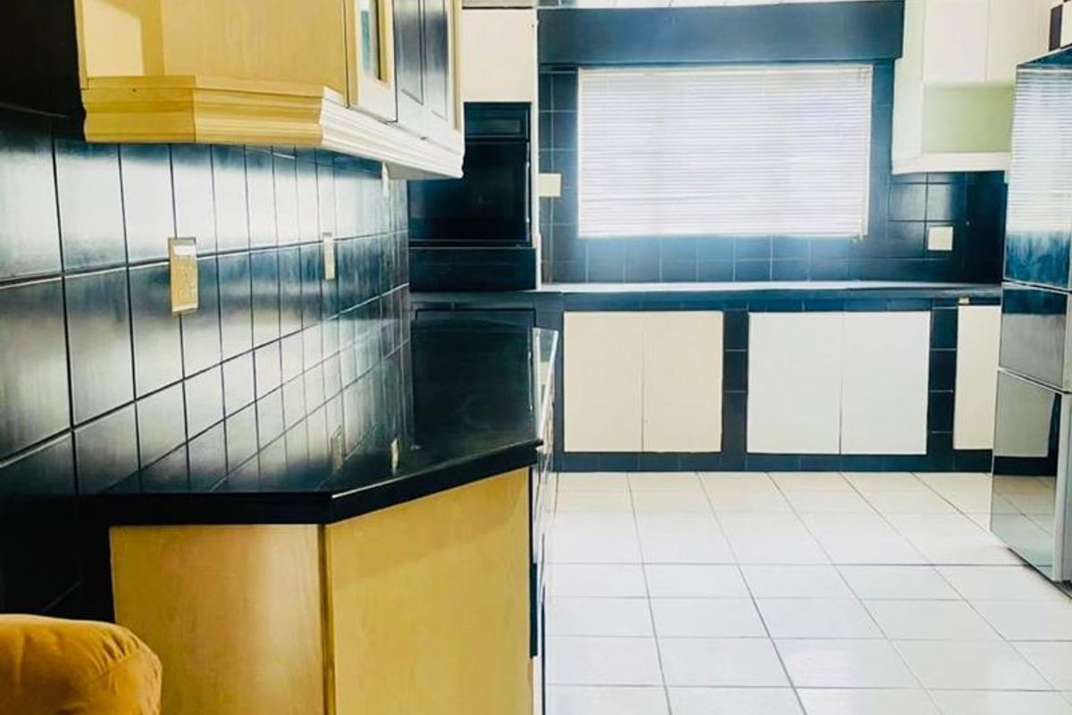 A spacious kitchen featuring high-contrast black and white cabinetry, tiled backsplash, and tiled flooring with ample counter space.