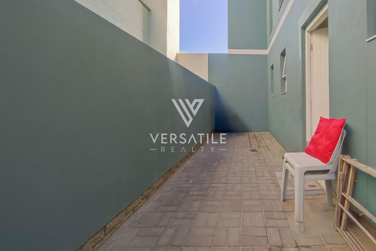 A narrow exterior side courtyard featuring paved flooring and painted boundary walls, providing a functional outdoor space.