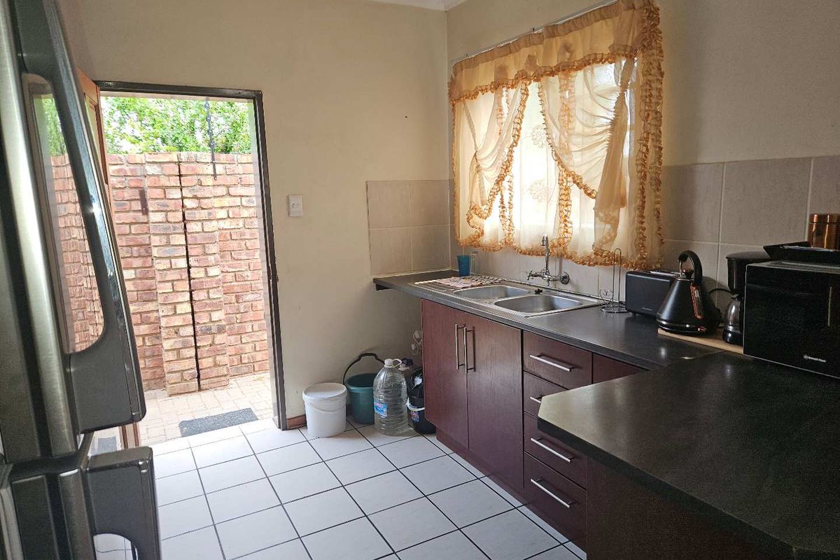 Functional kitchen featuring dark cabinetry, laminate countertops, double bowl sink, and direct access to an outdoor courtyard area.