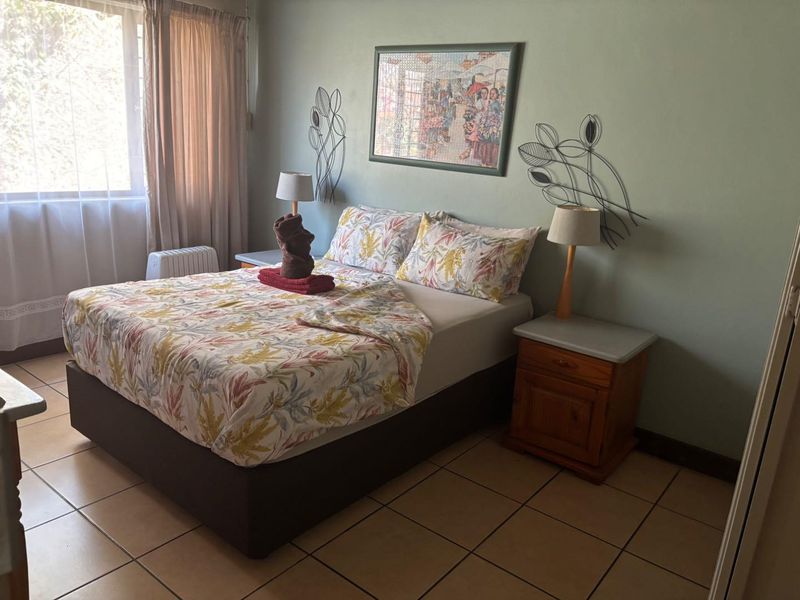 A functional bedroom featuring tiled flooring and natural light from the window, providing a comfortable space for rest.