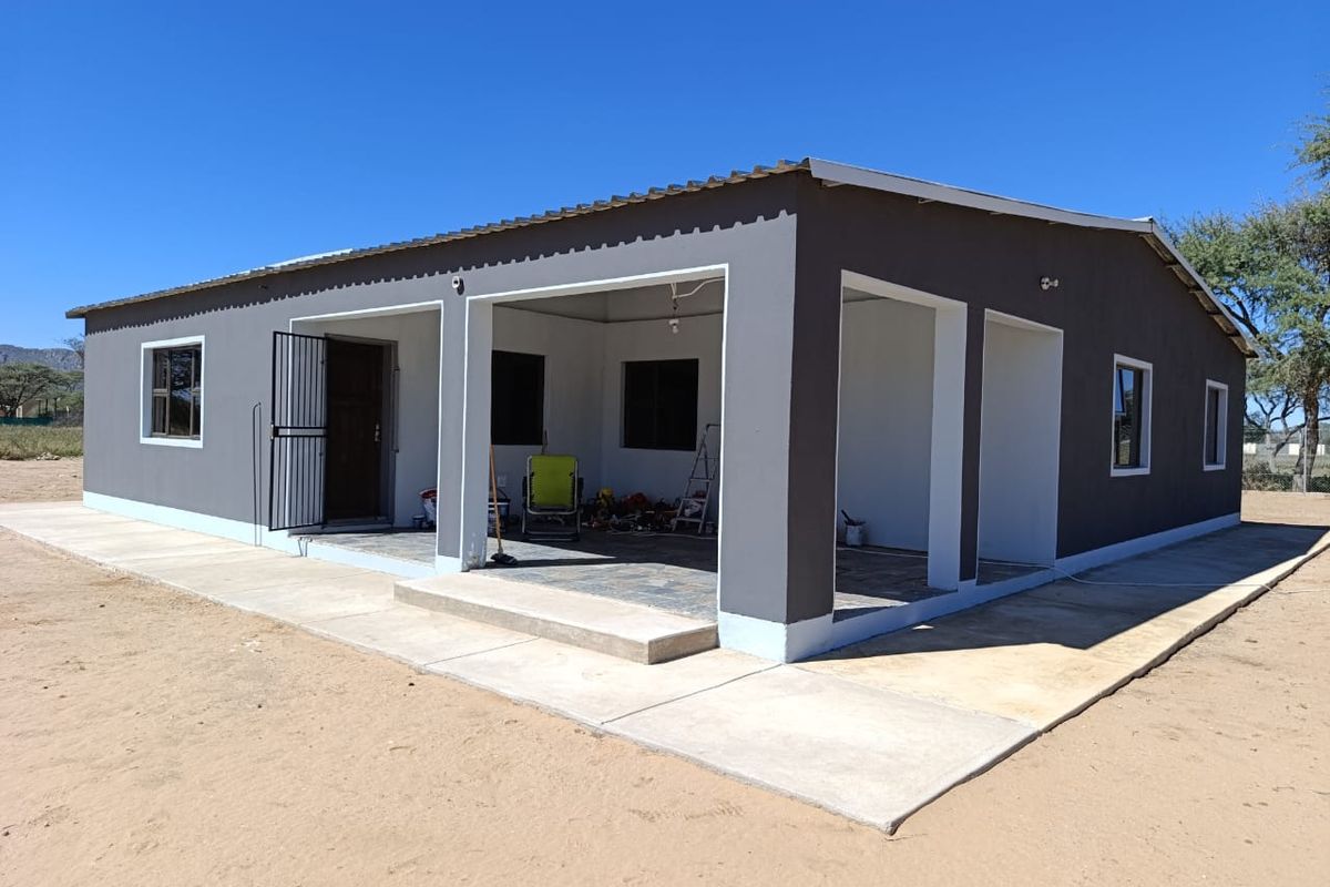 A modern single-story farmhouse exterior featuring a covered patio area, concrete walkways, and a clean, painted finish.