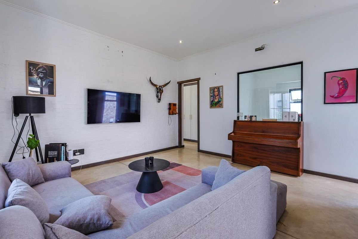 A living room featuring polished concrete flooring, recessed ceiling lighting, and a large interior window looking into an adjacent space.