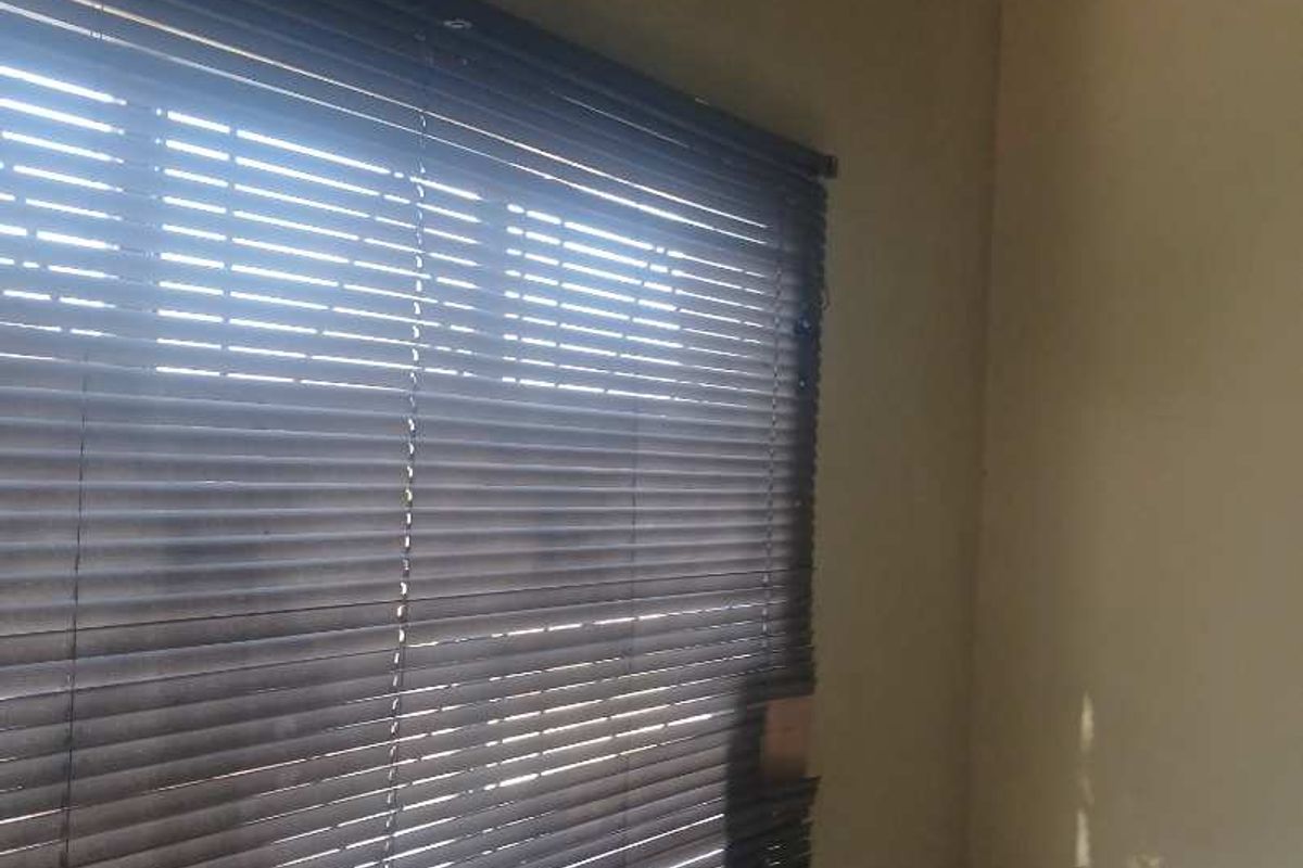 A simple interior space featuring installed venetian blinds, providing basic window coverage and natural light control.