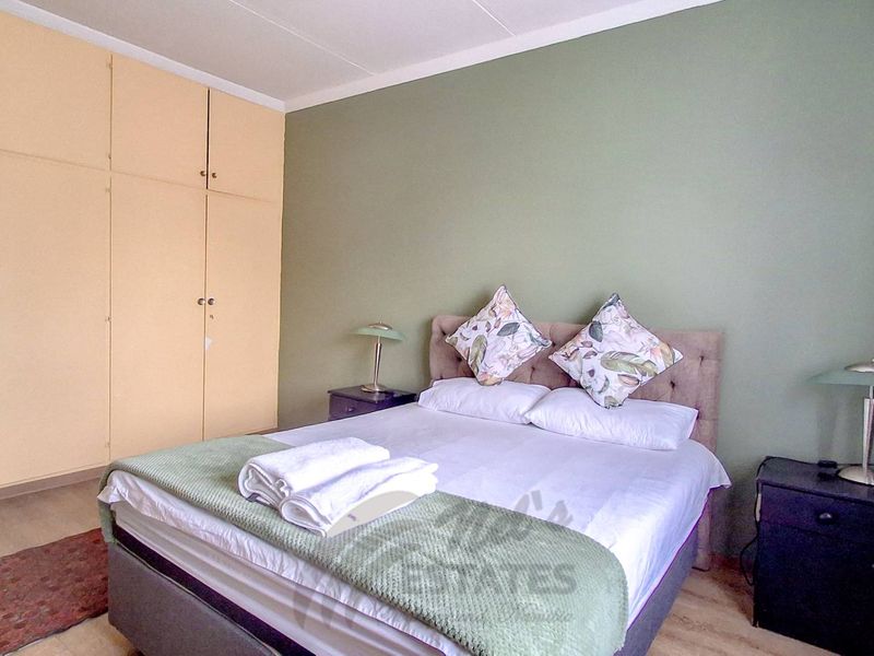 A bedroom featuring built-in cupboards and laminate flooring, providing a functional and neutral space.