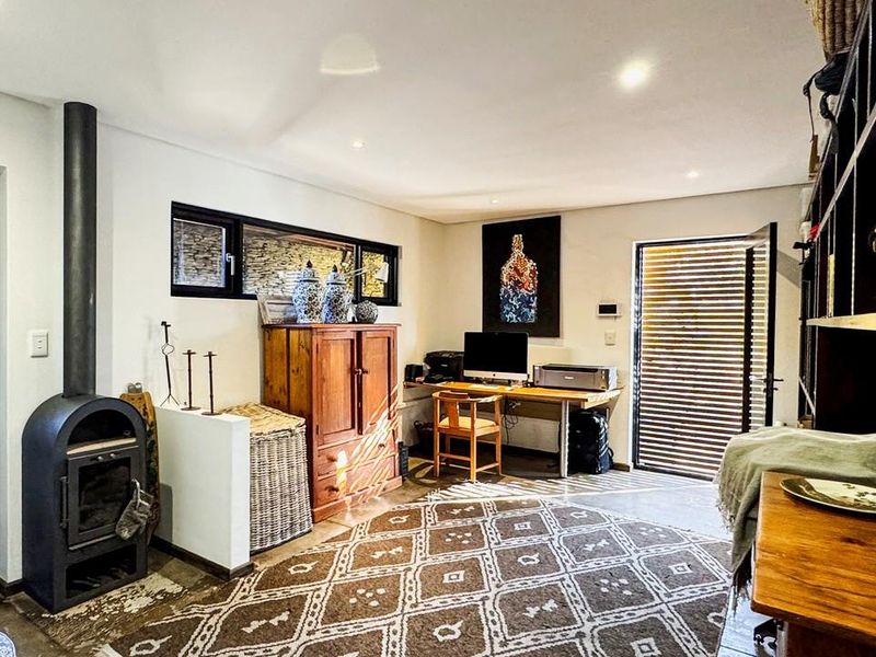 A versatile living space featuring a freestanding fireplace, built-in shelving, and direct access to outdoor areas through modern doors with horizontal slat blinds.