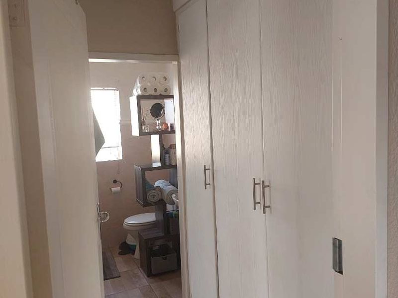 A functional hallway featuring built-in storage cupboards and tiled flooring, providing direct access to the adjacent bathroom area.