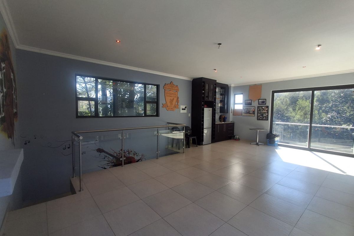 Spacious living area featuring tiled flooring, modern glass balustrade, built-in cabinetry, and large sliding doors providing access to an outdoor balcony.