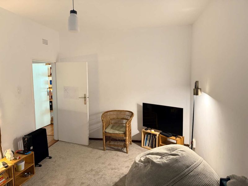 A simple bedroom featuring neutral carpet flooring and a standard ceiling vent, offering a blank canvas for potential interior design updates.