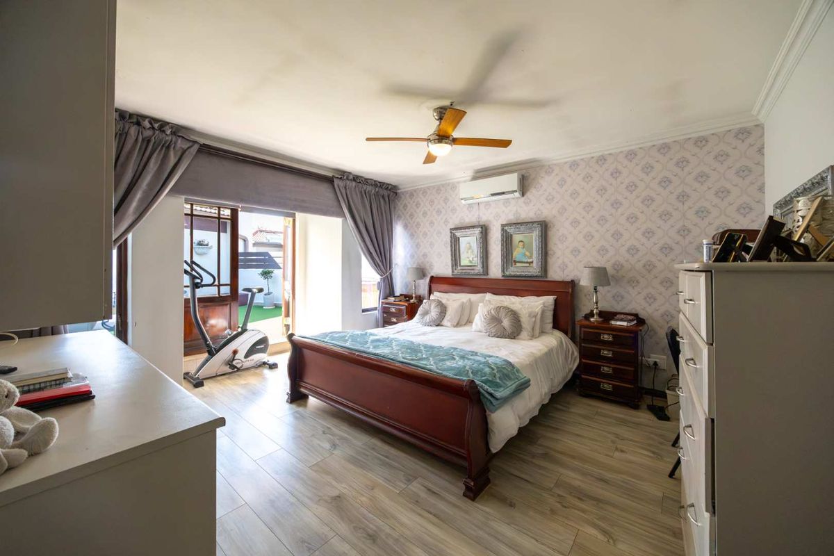 Spacious bedroom featuring laminate flooring, a ceiling fan, split-system air conditioning, and direct access to an outdoor patio area through sliding glass doors.