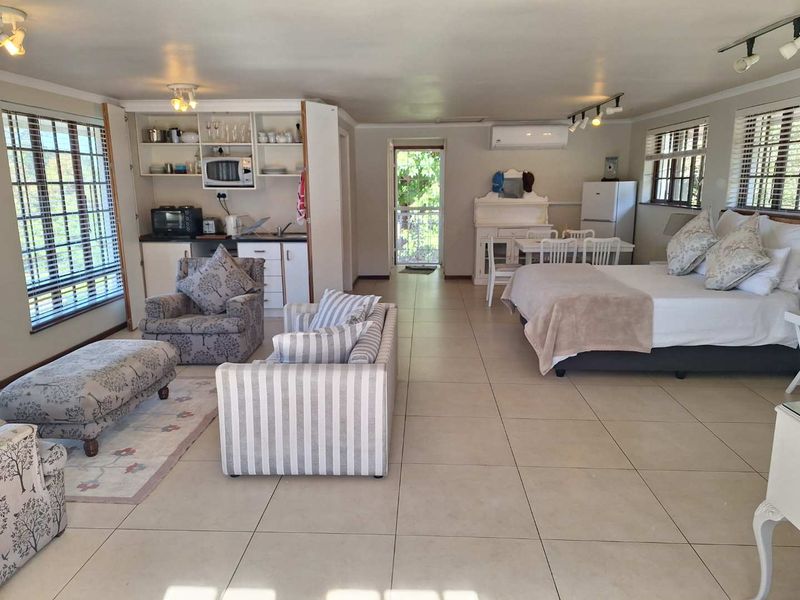 Spacious open-plan studio apartment featuring tiled flooring, a compact kitchenette, and a wall-mounted air conditioning unit.