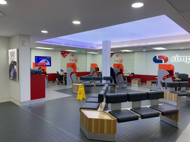 A modern, well-maintained retail banking interior featuring open-plan service counters, integrated seating, and professional recessed and cove lighting.