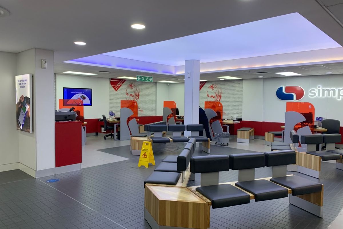 A modern, well-maintained retail banking interior featuring open-plan service counters, integrated seating, and professional recessed and cove lighting.