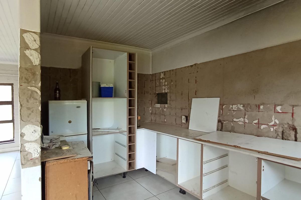 A kitchen area in need of renovation, featuring partially installed cabinetry and exposed wall surfaces, offering a blank canvas for custom finishes.