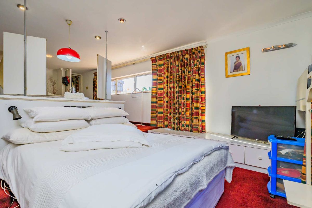 A bedroom featuring built-in cabinetry, recessed lighting, and large windows with curtains, finished with red carpeting.